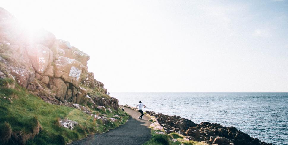 Free Image of Person walking along coastal path by a rocky shore 