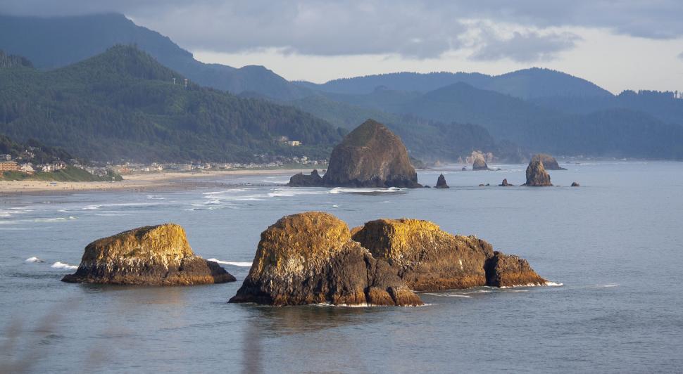 Free Image of Distant view of sea rocks with lush hills in the background 