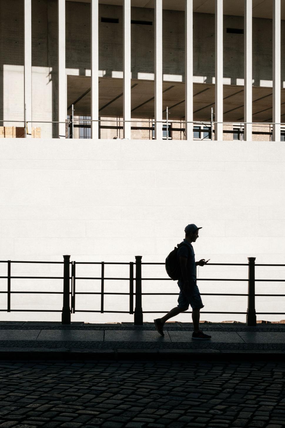 Free Image of Silhouette of a Person Walking Past Modern Building 