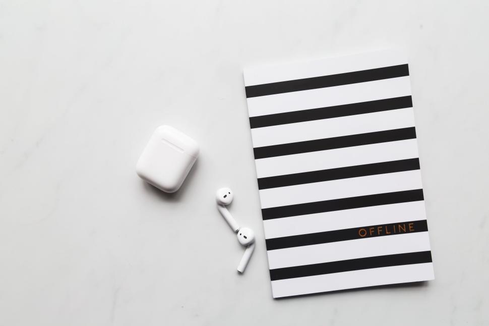 Free Image of Black and white striped notebook and wireless earbuds 