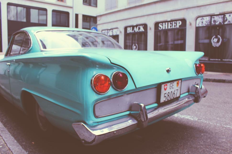 Free Image of A classic car parked on a city street near a shop. 