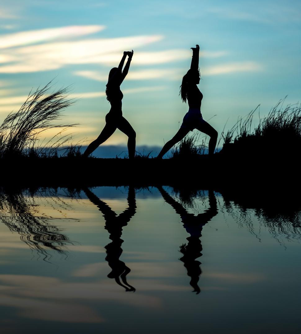 Free Image of Silhouette of two people performing yoga at sunset. 