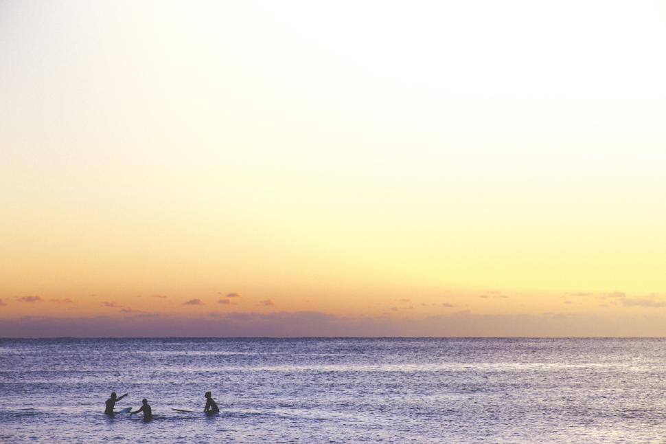 Free Image of Three people kayaking on the ocean at sunset 