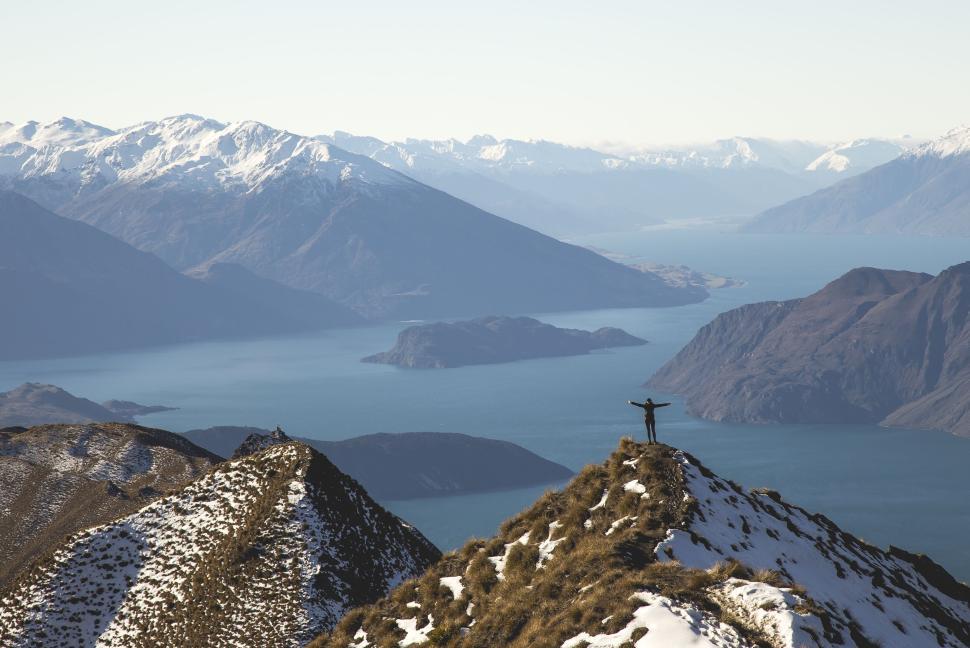 Free Image of Person standing on a snowy mountain ridge, vast landscape 