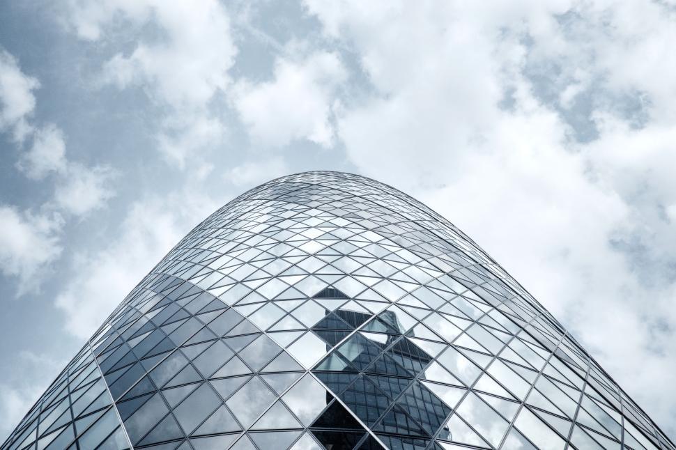 Free Image of Modern, reflective skyscraper amid scattered clouds. 