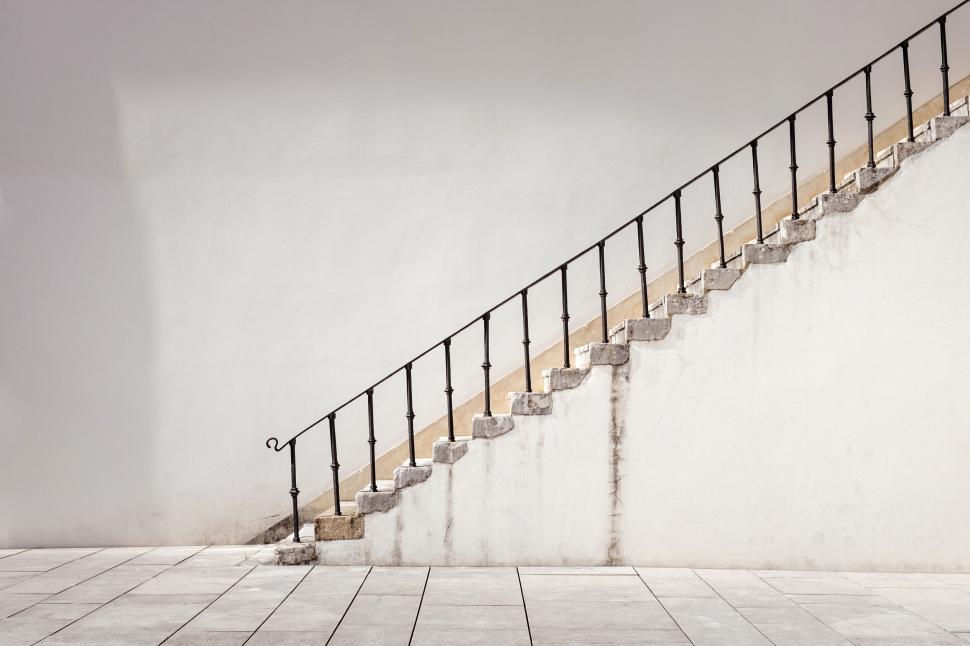 Free Image of Stone staircase with iron railing against white wall 