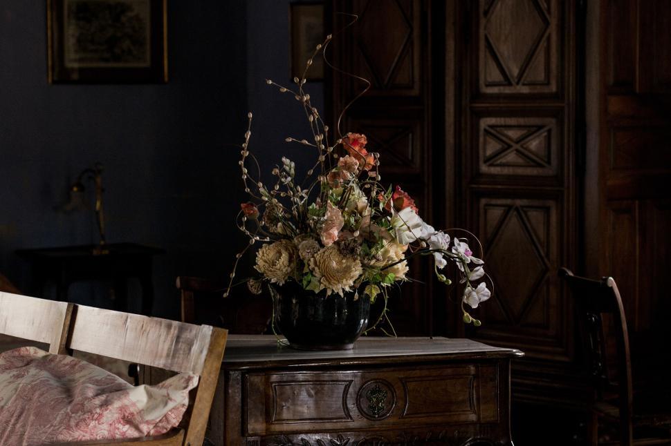 Free Image of Dimly lit room with antique furniture and flower vase. 