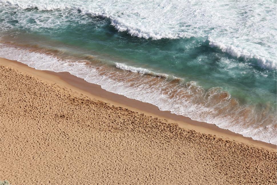 Free Image of Waves gently lapping onto a secluded sandy beach. 