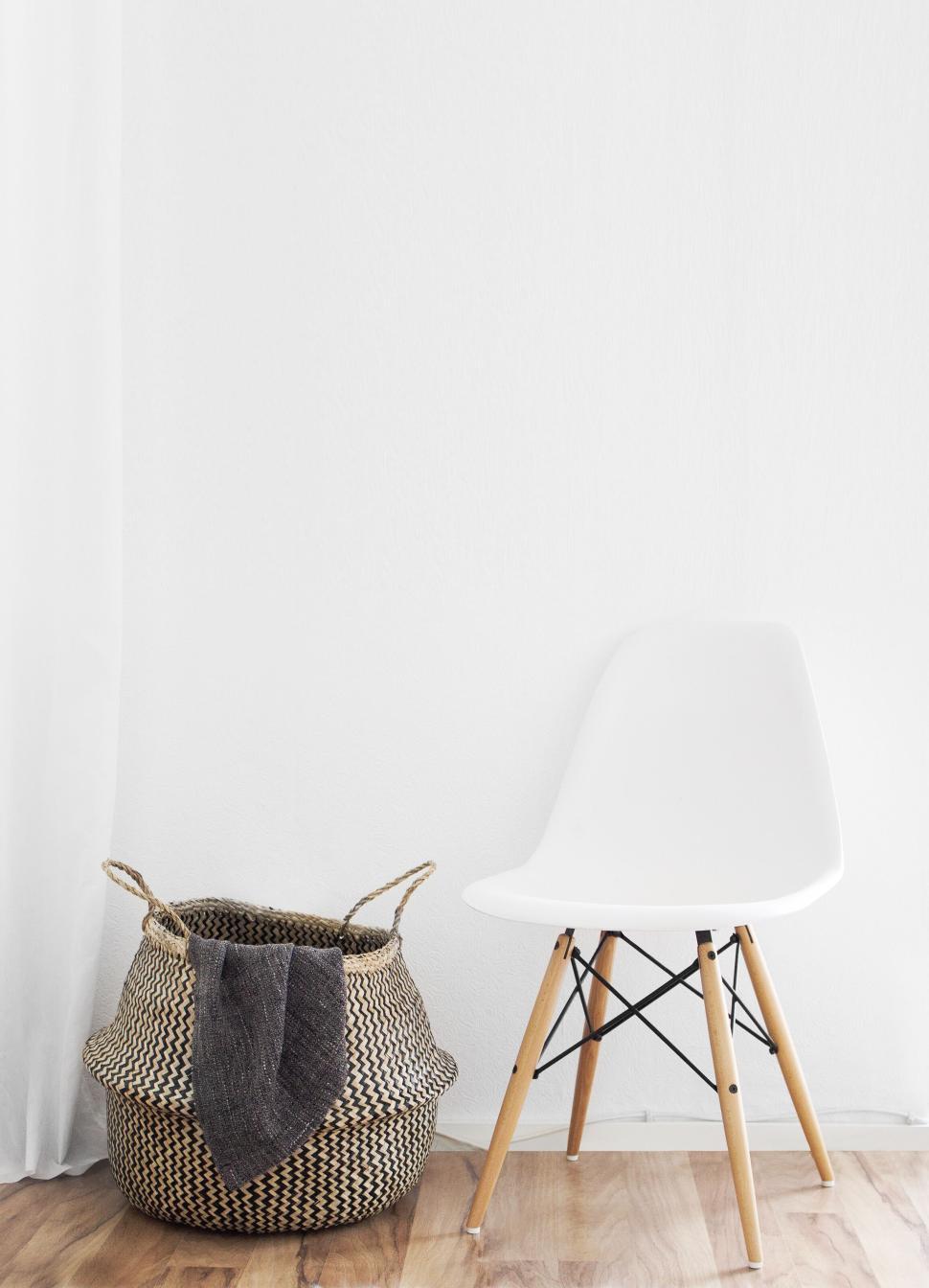 Free Image of Minimalist empty chair beside woven basket in corner 