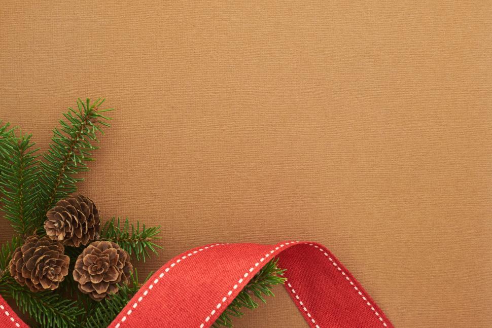 Free Image of Brown textured background with pinecones and red ribbon 