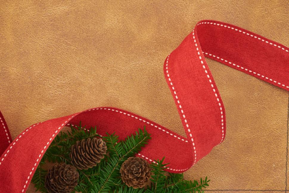 Free Image of Festive red ribbon with pinecones on rustic background. 