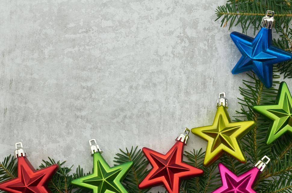 Free Image of Colorful star ornaments on evergreen branch backdrop 
