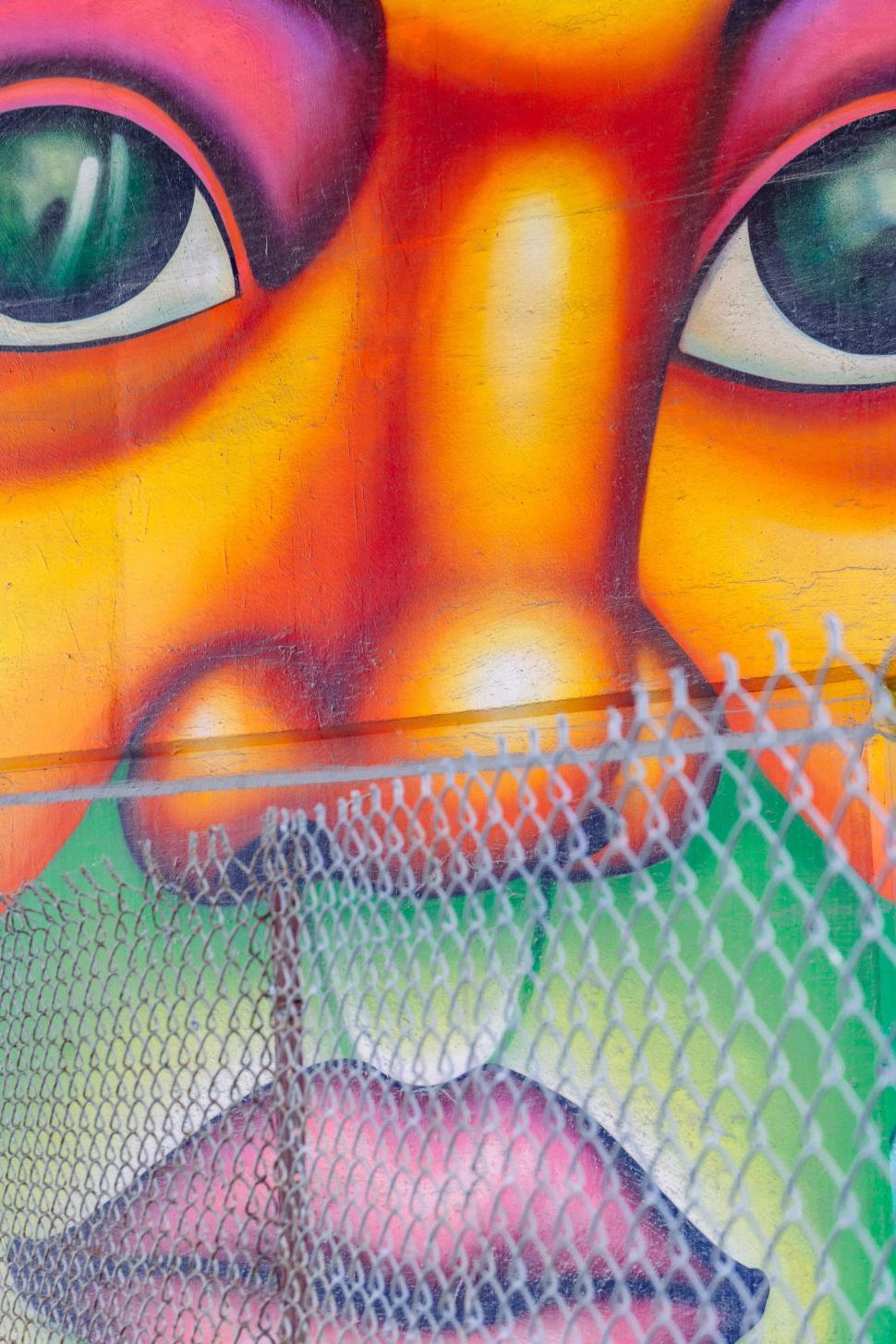 Free Image of Colorful mural depicting a face behind a metal fence 