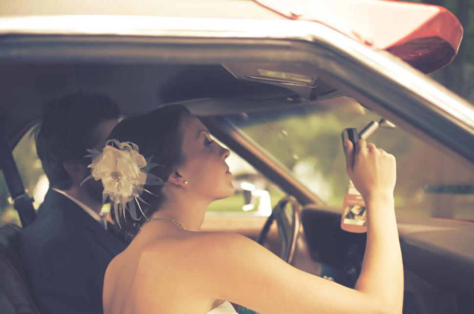 Free Image of Bride holding car mirror inside vehicle on wedding day 