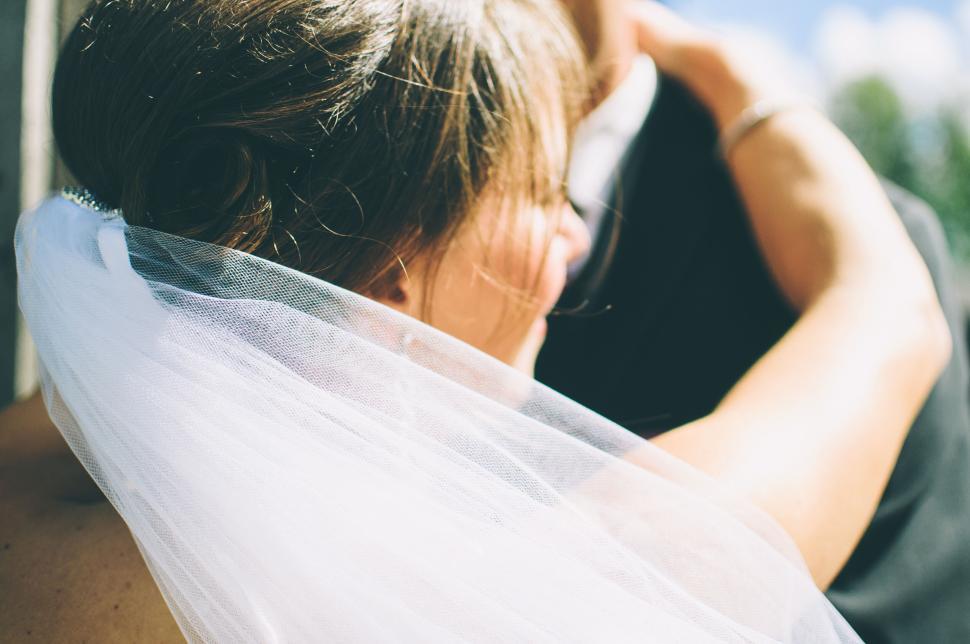 Free Image of Bride embracing groom outside in sunlight, close shot 