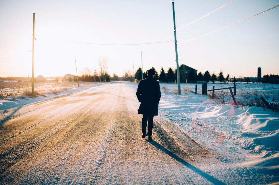 Free Image of Person walks along snowy road during winter sunset 