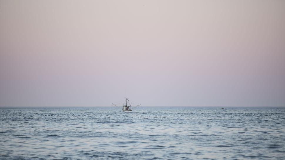 Free Image of Fishing boat sailing in calm open sea at dusk. 