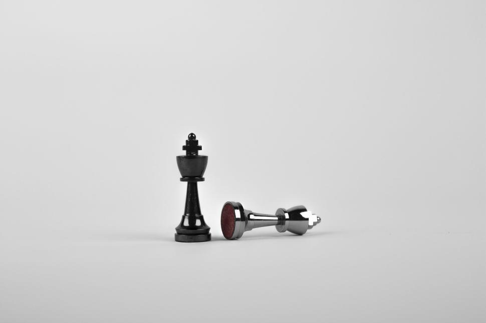 Free Image of Black king stands while silver piece lies on its side 