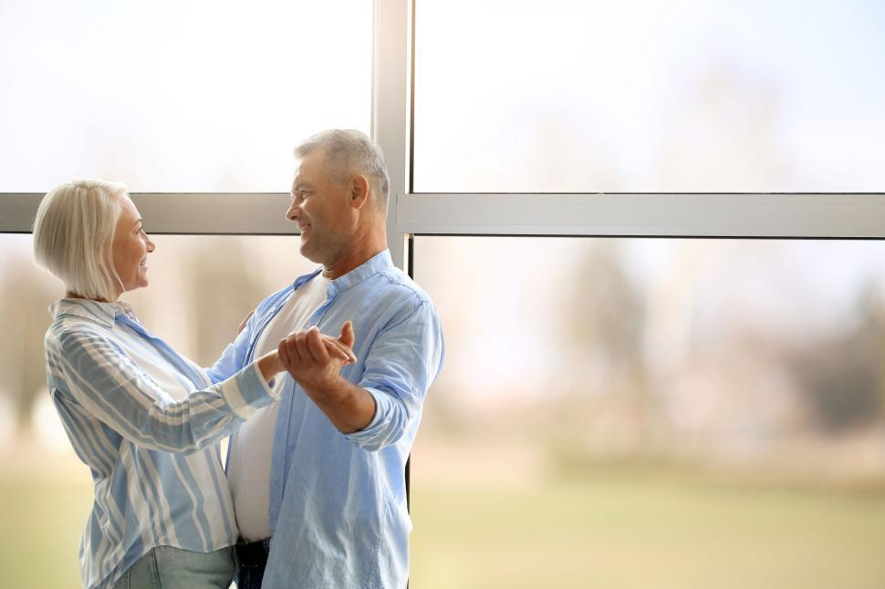 Free Image of Elderly couple dancing in front of large window 