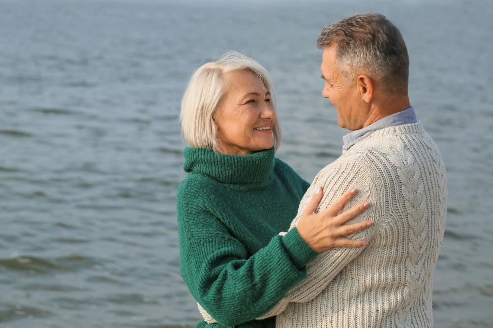 Free Image of Smiling elderly couple embraces by riverbank. 