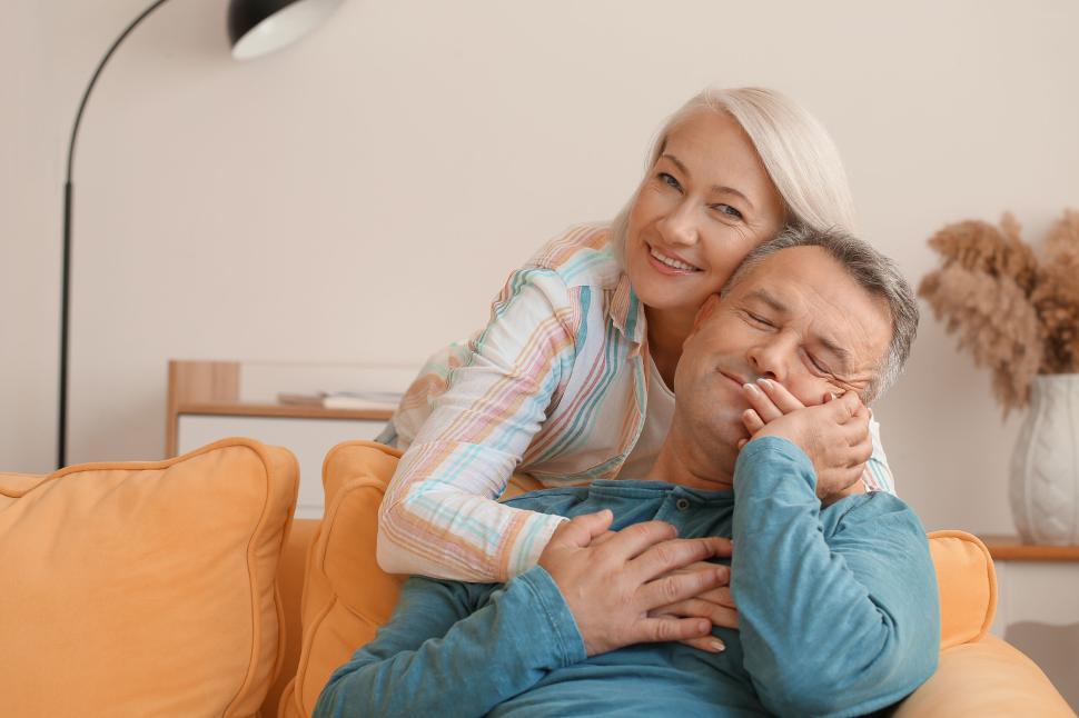 Free Image of Woman lovingly embraces man on yellow couch. 