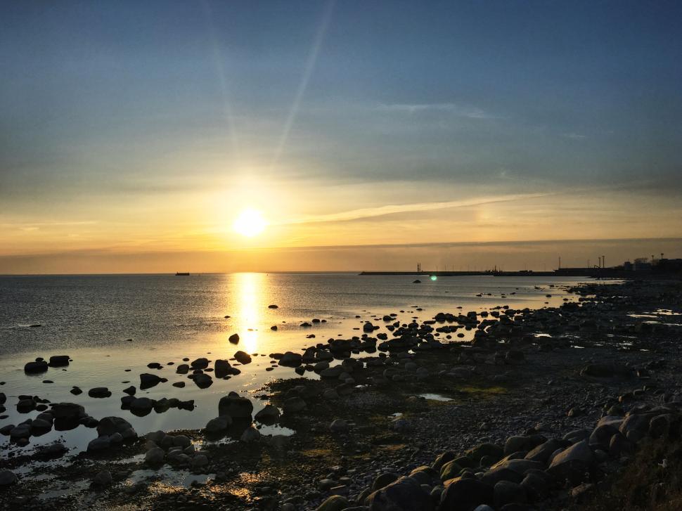 Free Image of Rocky seashore at sunrise with soft golden light. 