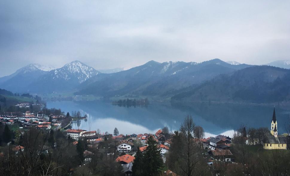 Free Image of Idyllic village beside a still lake with mountain backdrop 