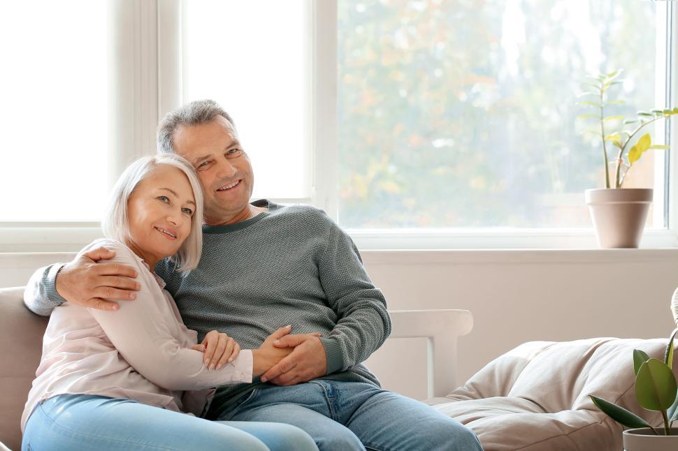 Free Image of Elderly couple sitting on couch in sunny room. 
