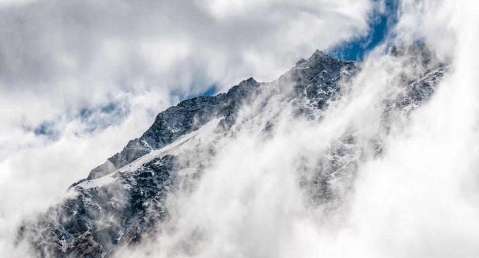 Free Image of Mountain peak shrouded in mist and clouds, majestic view 