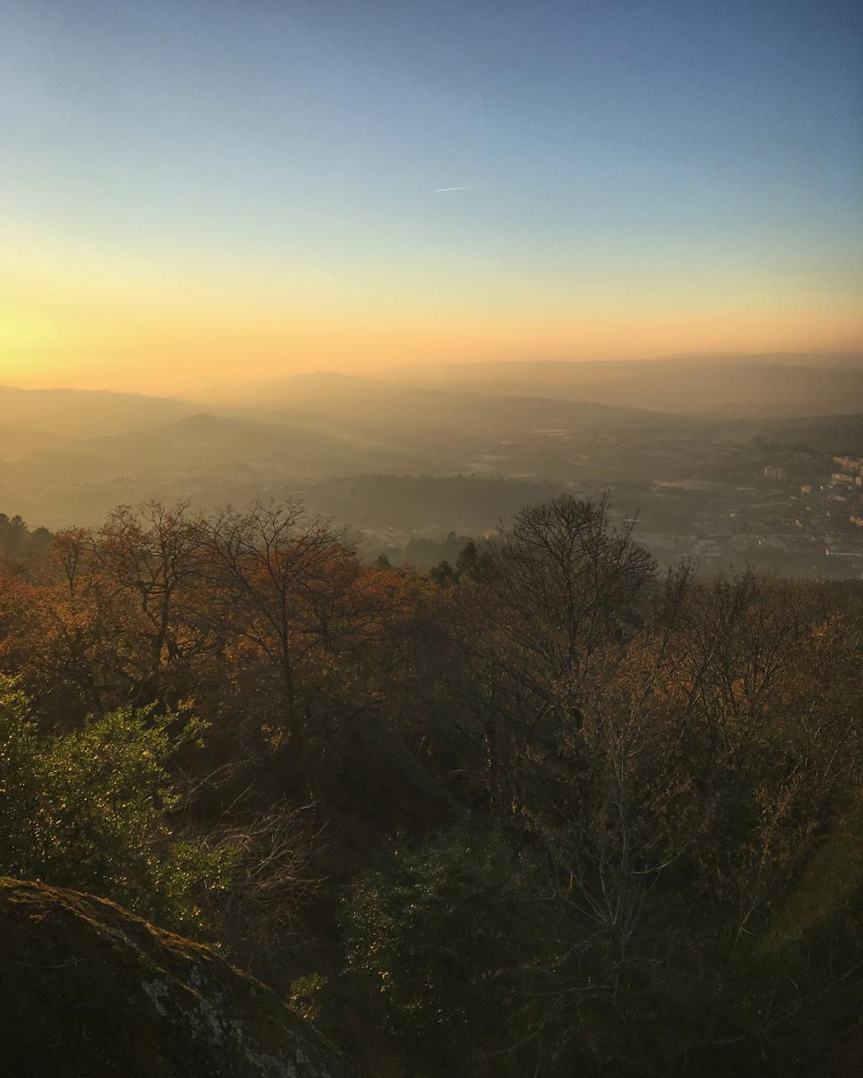 Free Image of Sunset view over a scenic forest and distant mountains. 