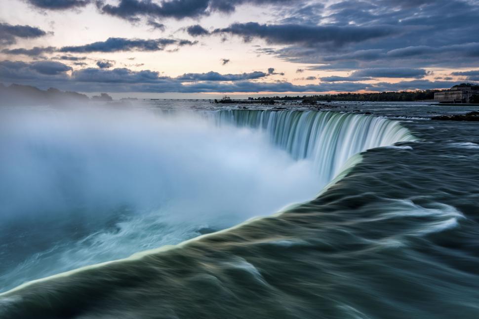 Free Image of Powerful waterfall cascading into misty river below 