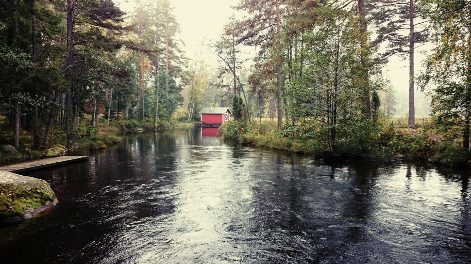 Free Image of Small red cabin by the river surrounded by dense forest 