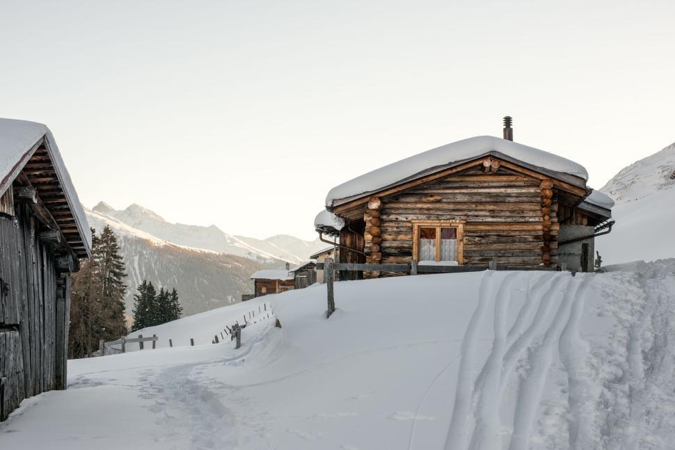 Free Image of Cosy mountain log cabin in snow-covered winter landscape. 
