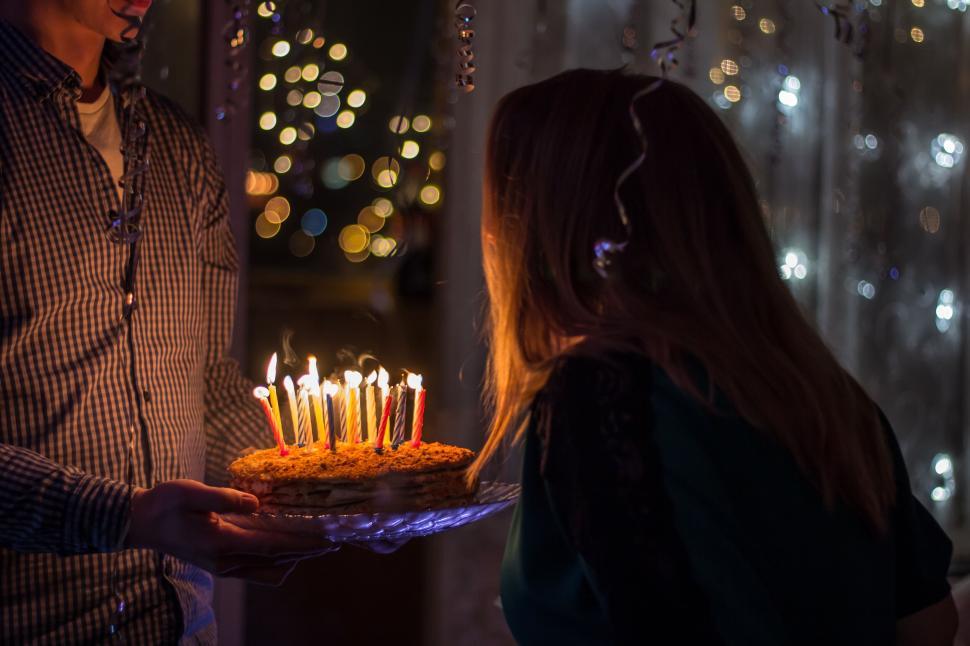 Candlelit birthday cake presented by someone