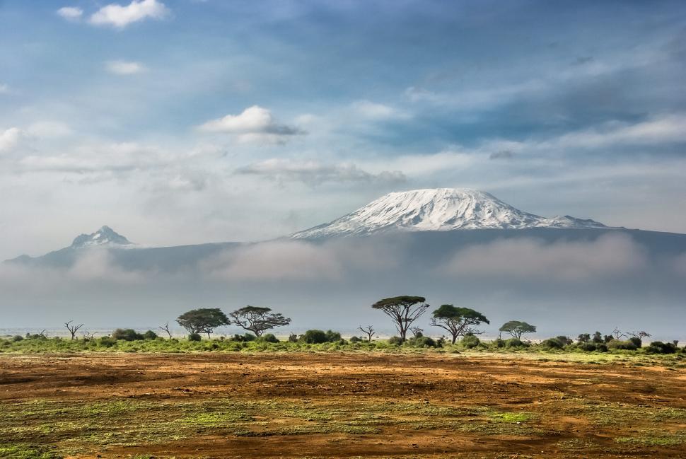 Free Image of Majestic snow-capped mountain peak over green plain 