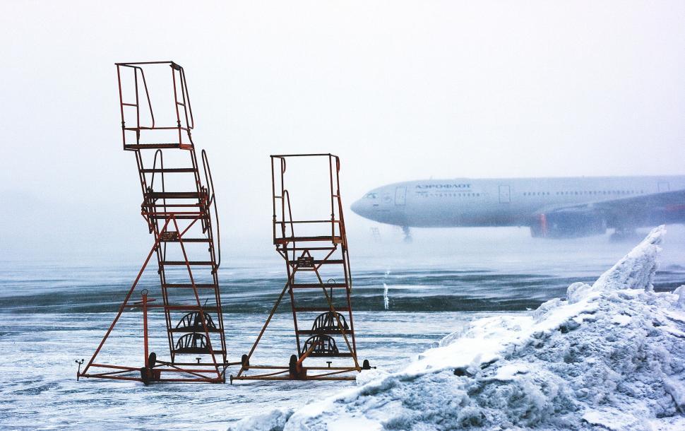 Free Image of Winter airport scene with plane and equipment in foggy 