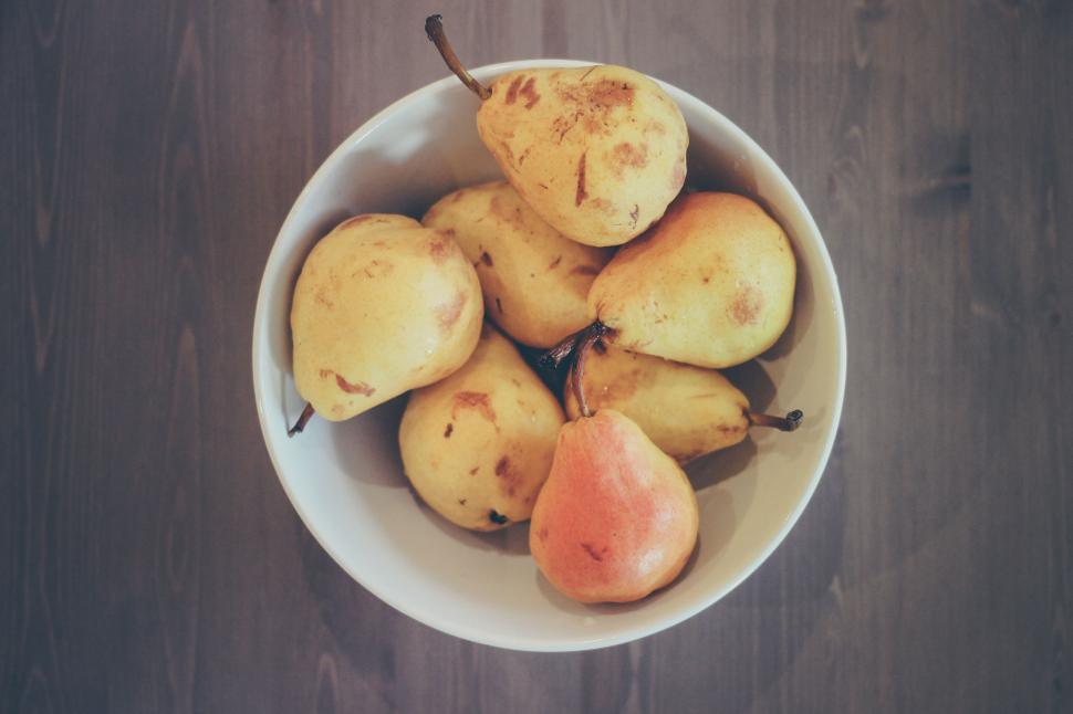 Free Image of A bowl filled with ripe pears on a wooden table 