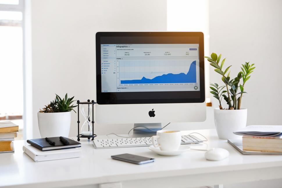 Free Image of Workspace with computer, plant, coffee in bright office 