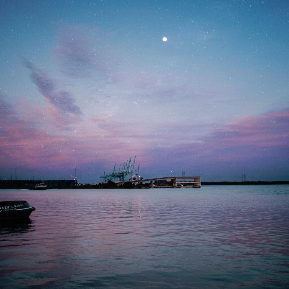 Free Image of Scenic harbor at dusk with cranes and a vibrant sky 