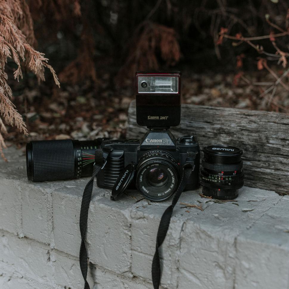 Free Image of Vintage Canon AE-1 camera with attachments on a wall. 