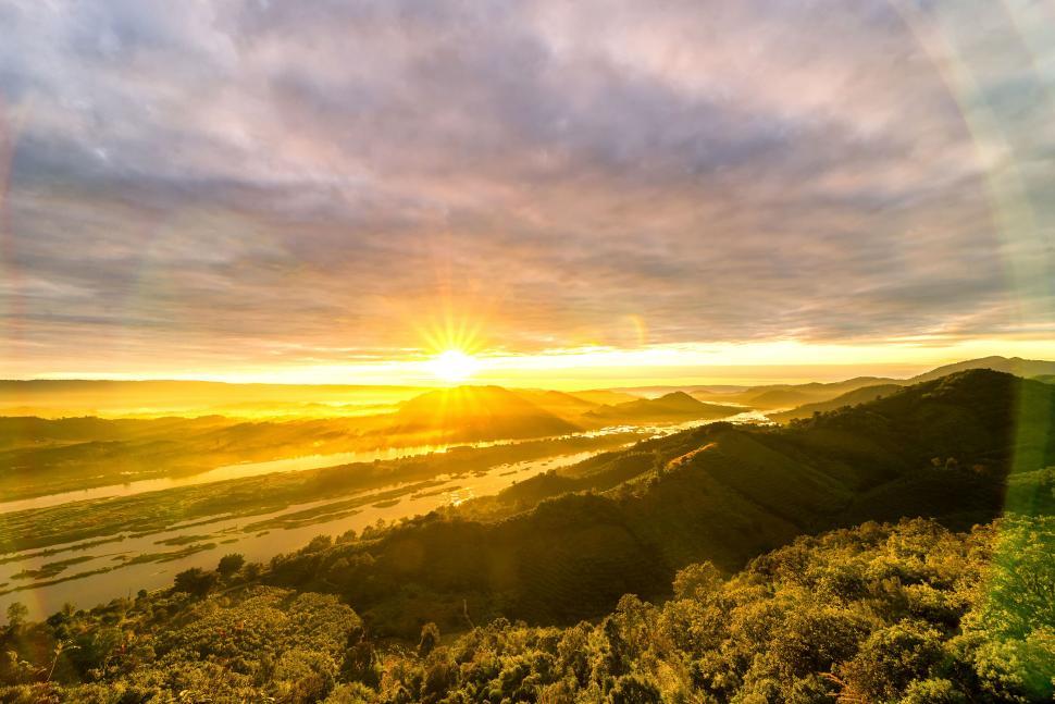 Free Image of Sunrise over lush hills with a winding river view 