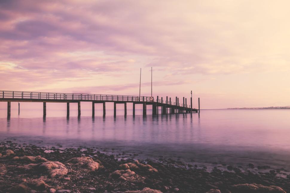 Free Image of Serene view of a pier over calm water at sunset 