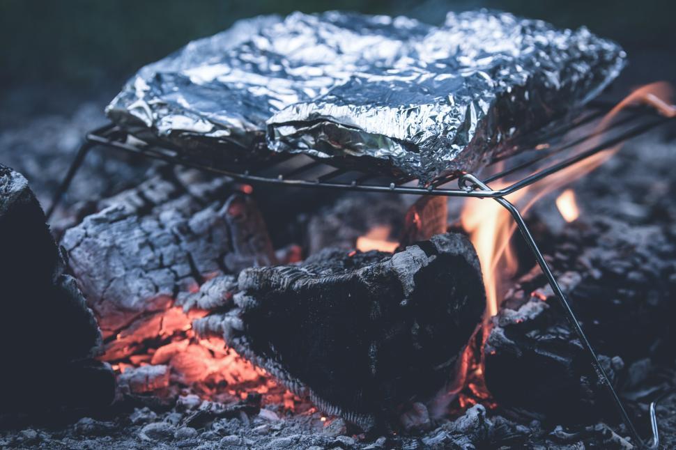 Free Image of Campfire cooking with foil on grill over open flame 