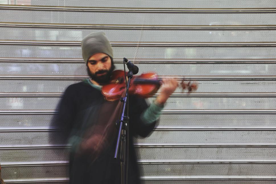 Free Image of Man playing violin in front of closed metal shutters 