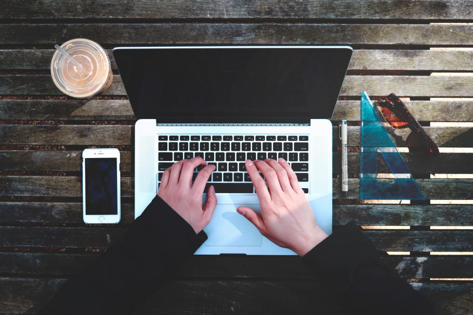 Free Image of Person working on laptop with phone and coffee nearby. 