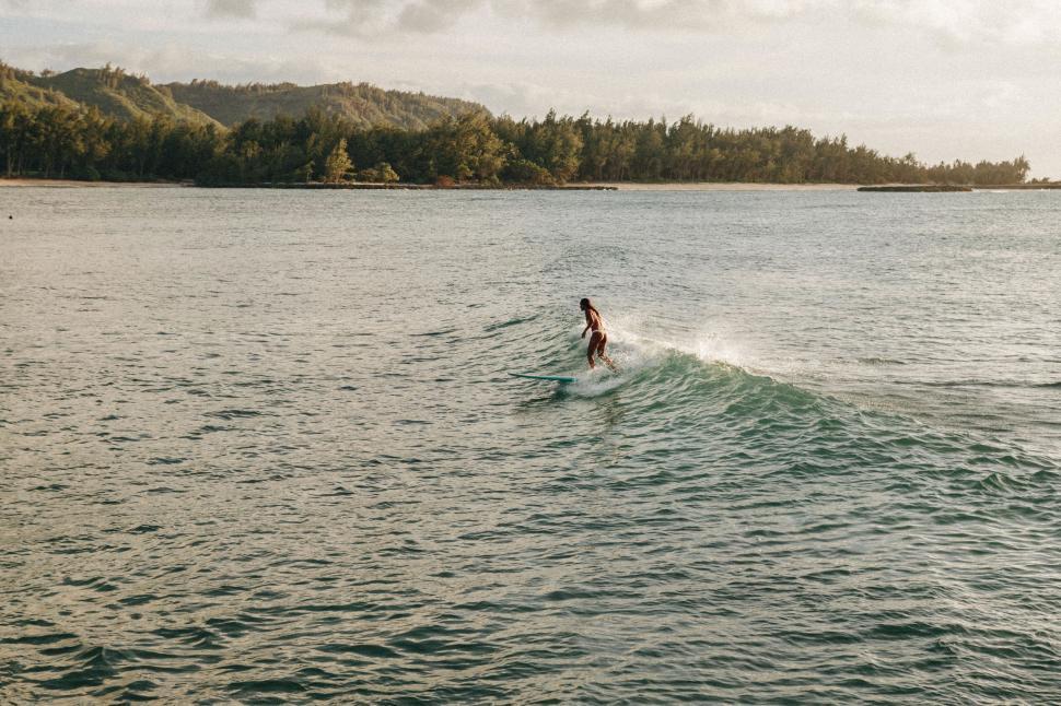 Free Image of Surfer riding a wave on a sunny coastal day 