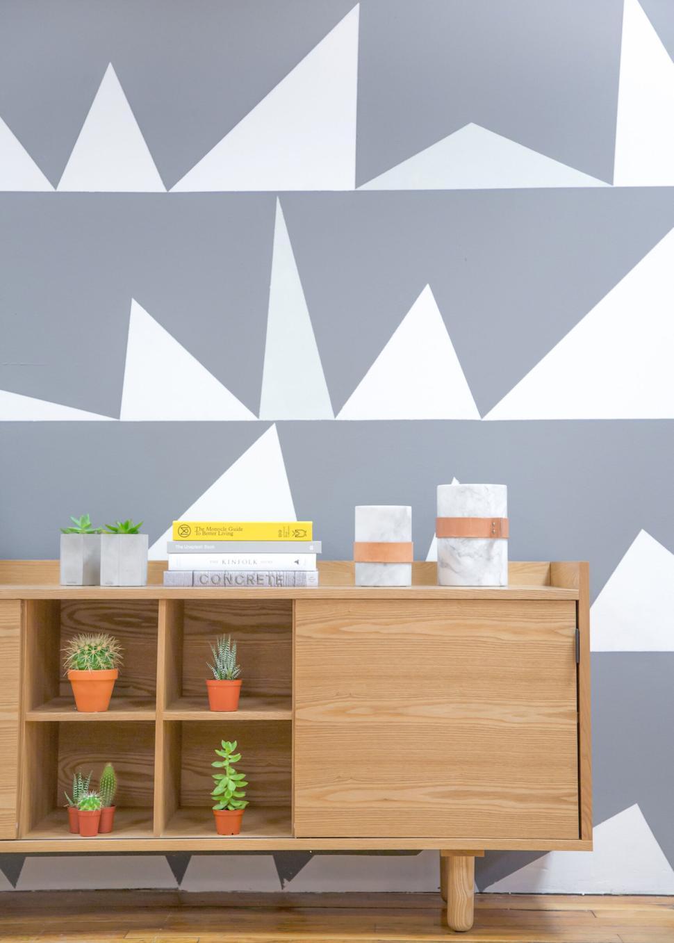 Free Image of Wooden dresser with books and plants against pattern wall 