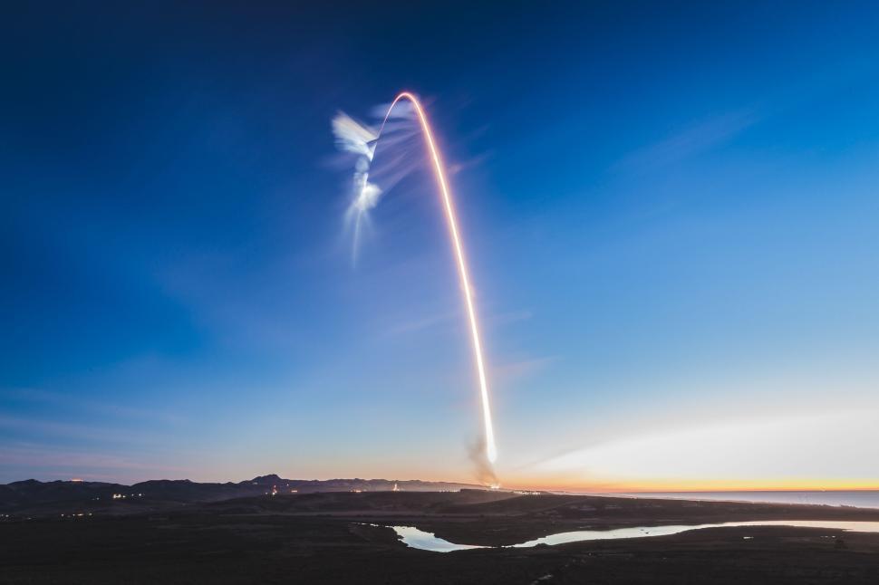 Free Image of Rocket creating a dramatic arcing light streak at sunrise 