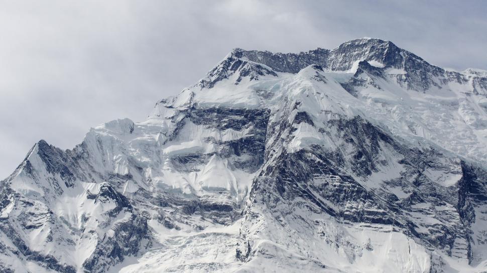 Free Image of Snow-capped mountain peaks under a cloudy sky 