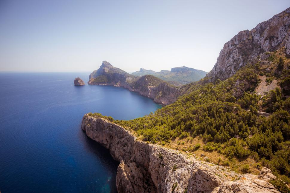 Free Image of Aerial view of coastal cliffs and clear blue sea at noon. 